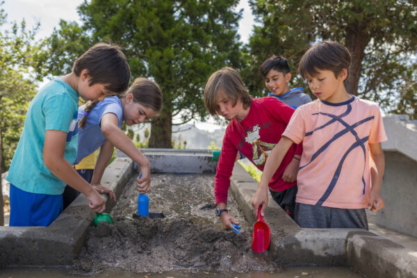Five children digging in sand in the Forces that Shape the Bay exhibit