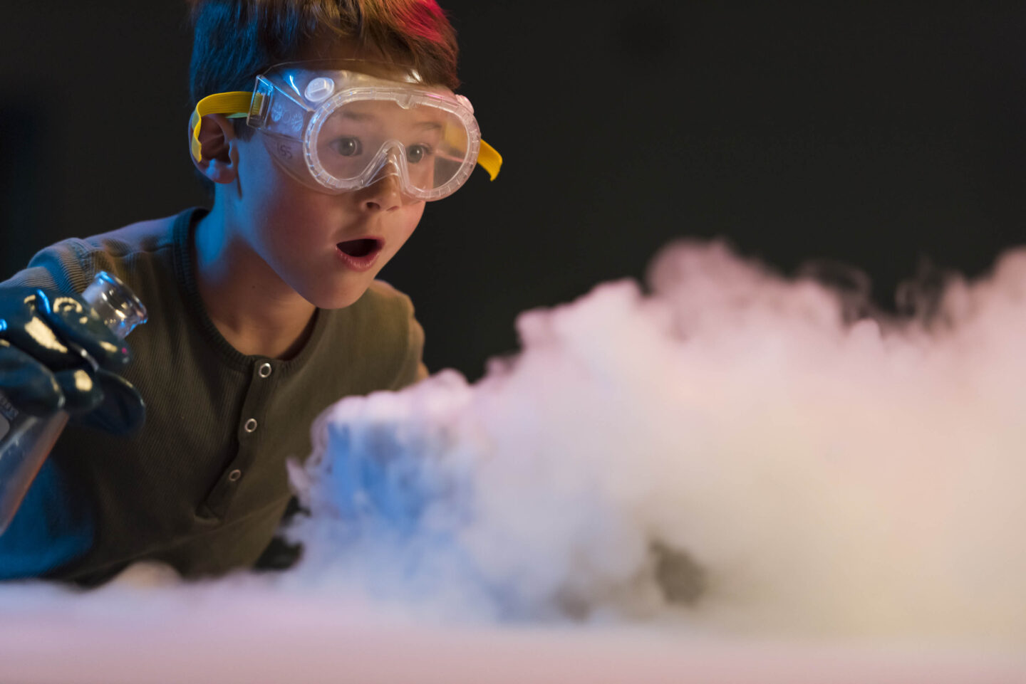 A young person wears safety goggles while conducting a science experiment.