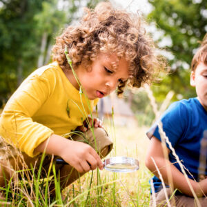 A child uses a magnifying glass to investigate nature