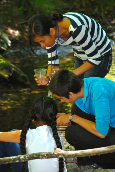 Three youth investigating water at a creek