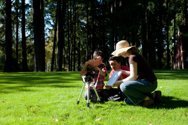 A woman and two children observing the sun using a solar viewer device