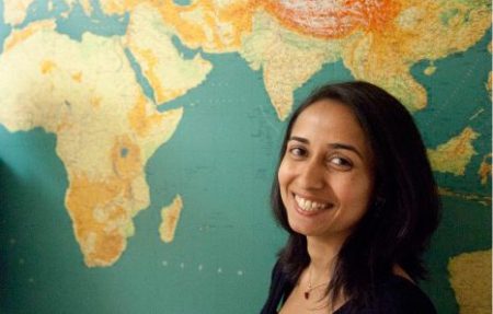Priya Moorjani in front of a world map